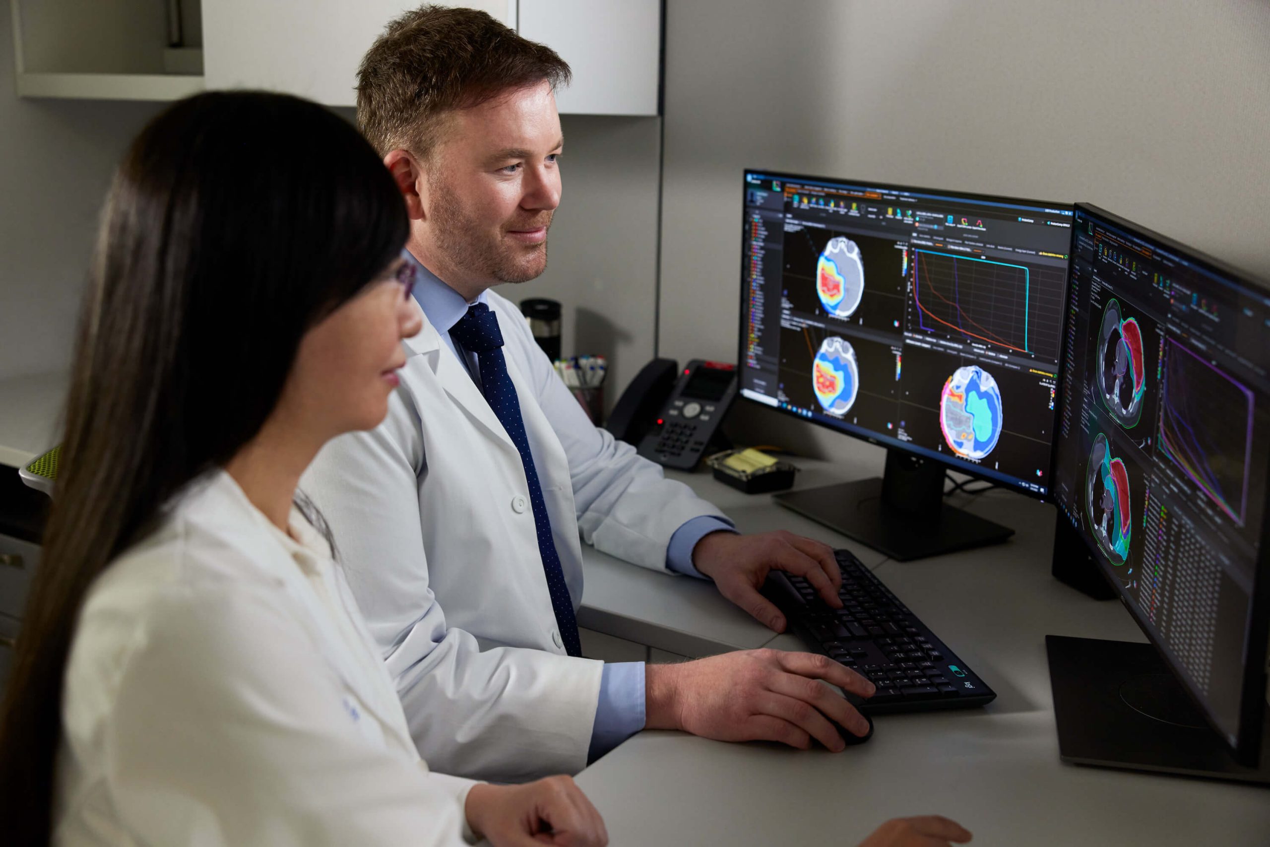 Two doctors reviewing scans on computer screens